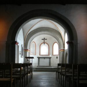 Blick durchs Kirchenschiff in den Altarraum einer kleinen romanischen Dorfkirche aus der Zeit um 1100